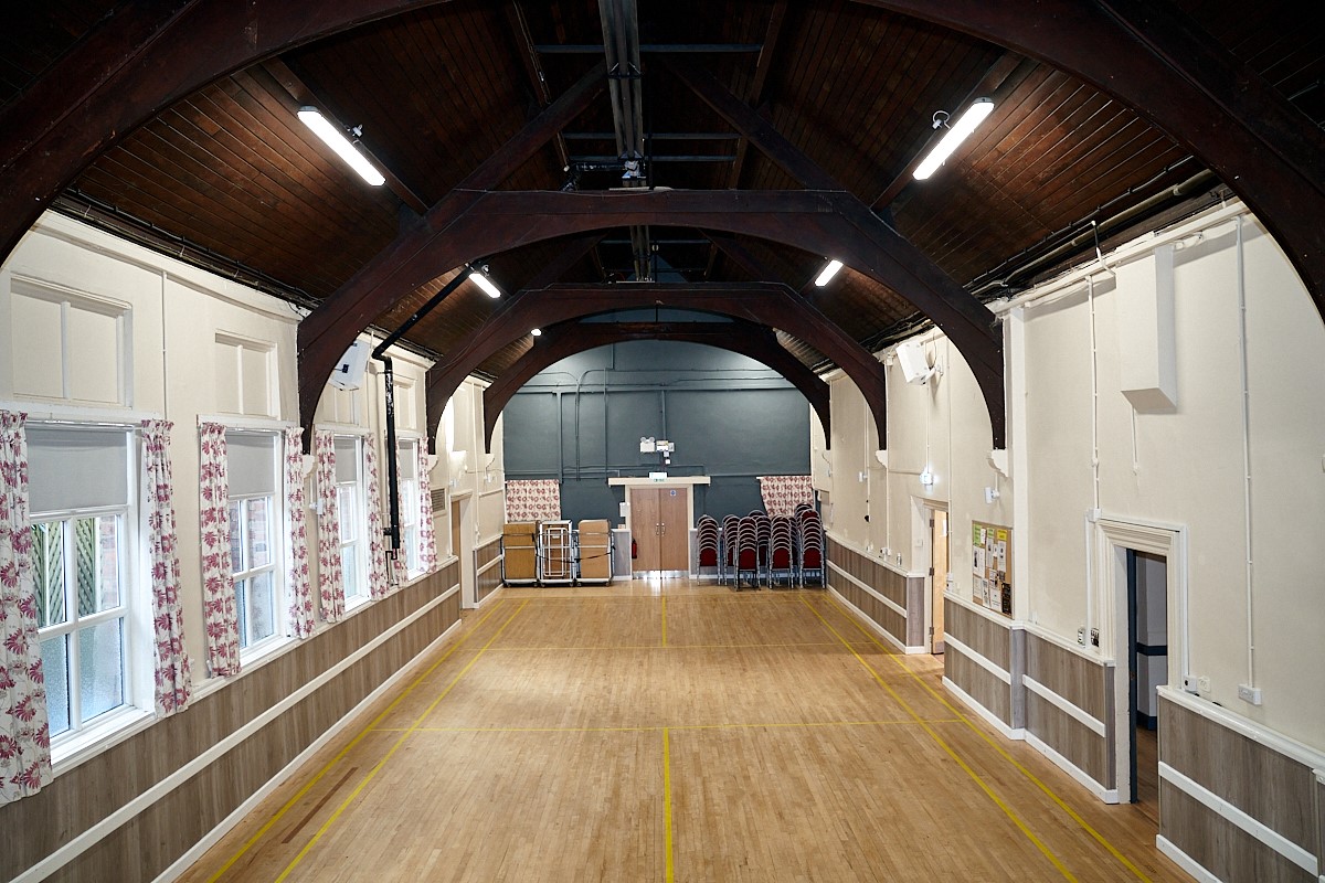 Large main hall with vaulted ceiling and a raised curtained stage at one end including a 3 metre ceiling mounted projection screen